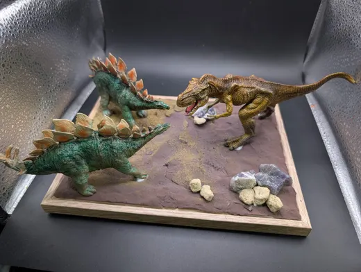 ステゴサウルスとティラノサウルスが向かい合う砂地のジオラマ